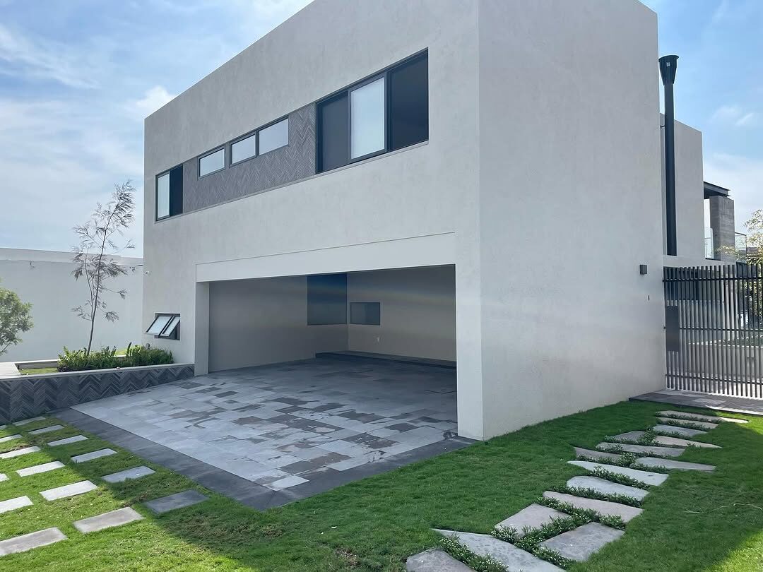Casa MS en Puerta Las Lomas, terminada: dos volúmenes blancos con cochera abierta y jardín.