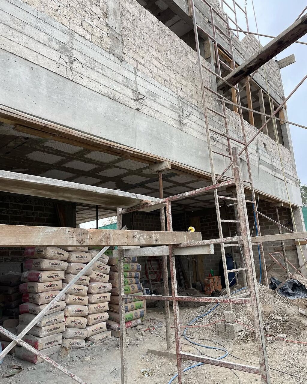Avance de obra en Puerta Las Lomas: estructura de concreto, andamios y bultos de cemento.